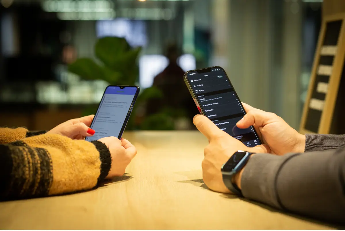Mãos de duas pessoas usando um celular para explorar aplicativos relacionados ao design de produto.